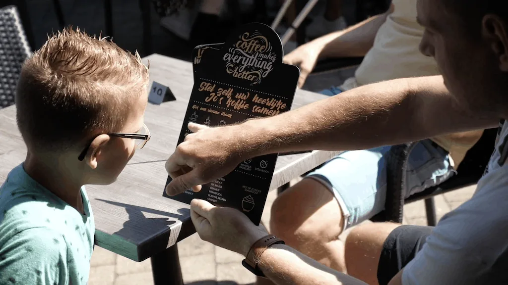 Vader en zoon bekijken een menukaart op een terras
