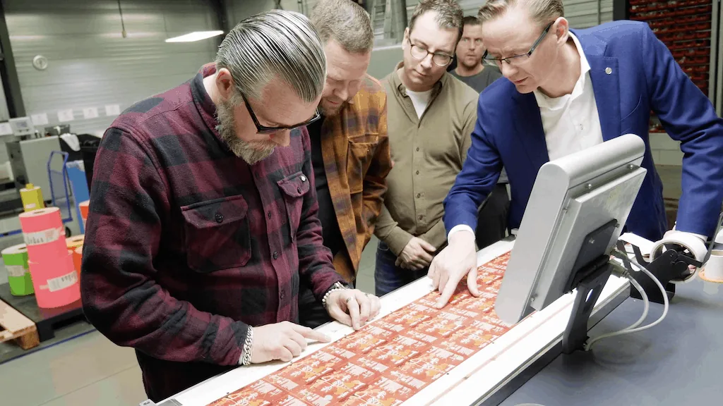 Vier mannen bekijken drukwerk aan een machine